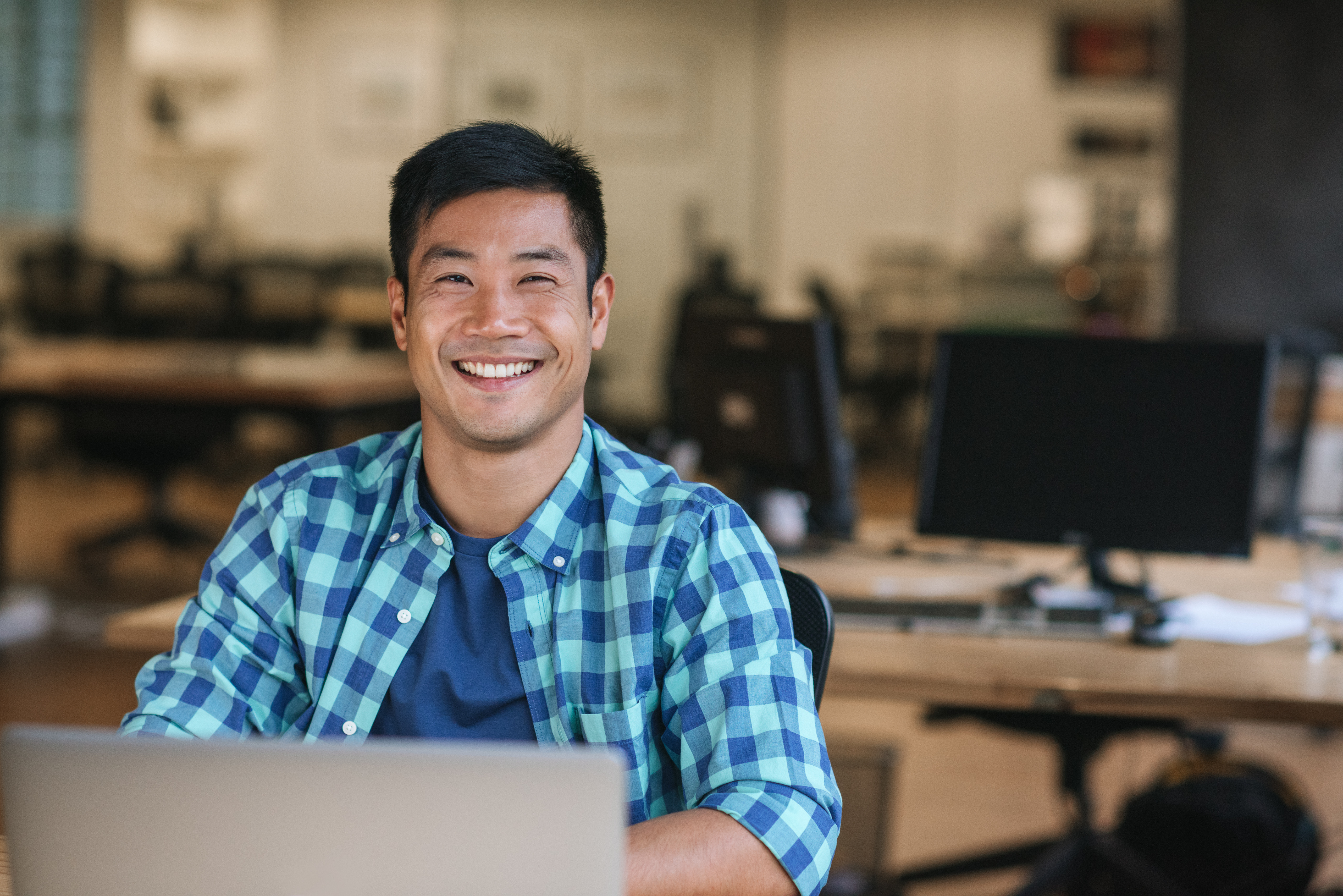 man smiling looking up from laptop