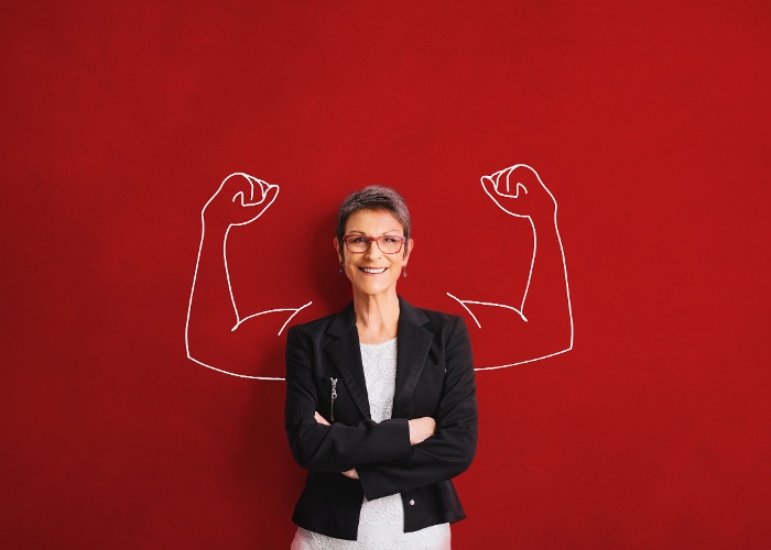 woman with cross arms standing in front of muscular arms on a red background