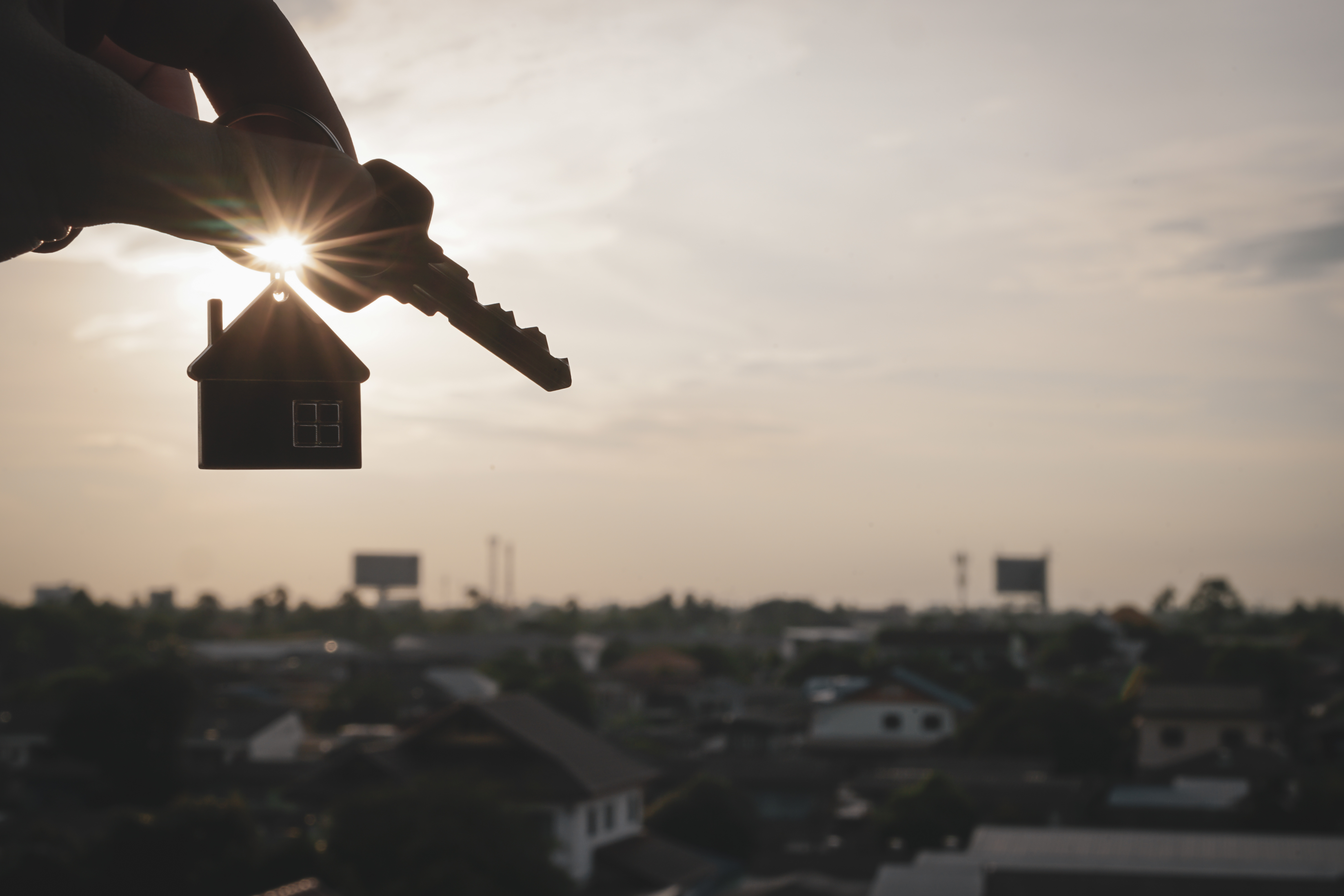 home keychain being held up against the suset