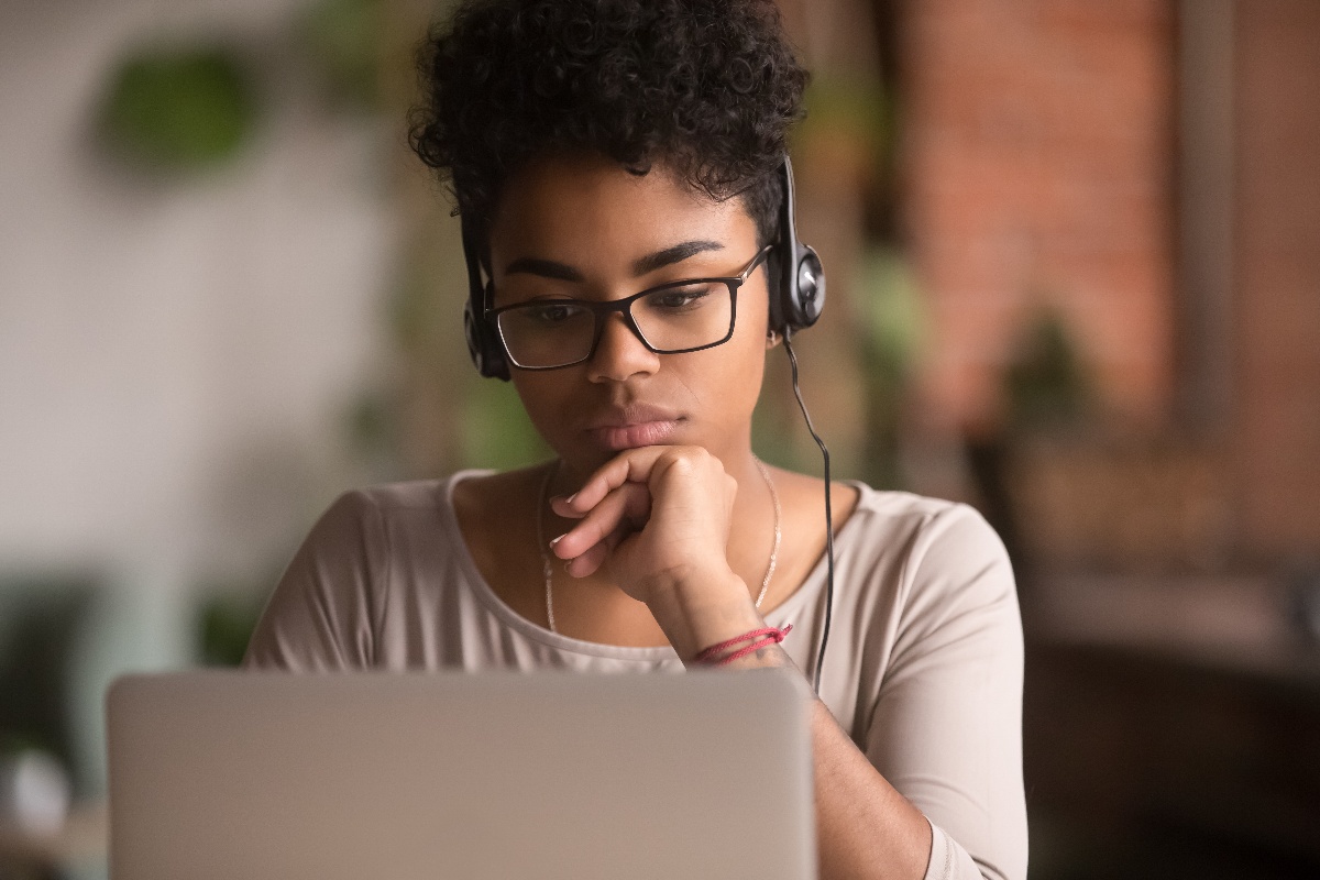 woman looking at laptop screen with headphones on