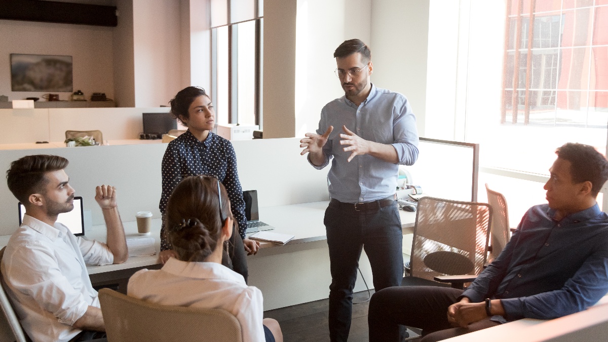 group of business people chatting by office desks