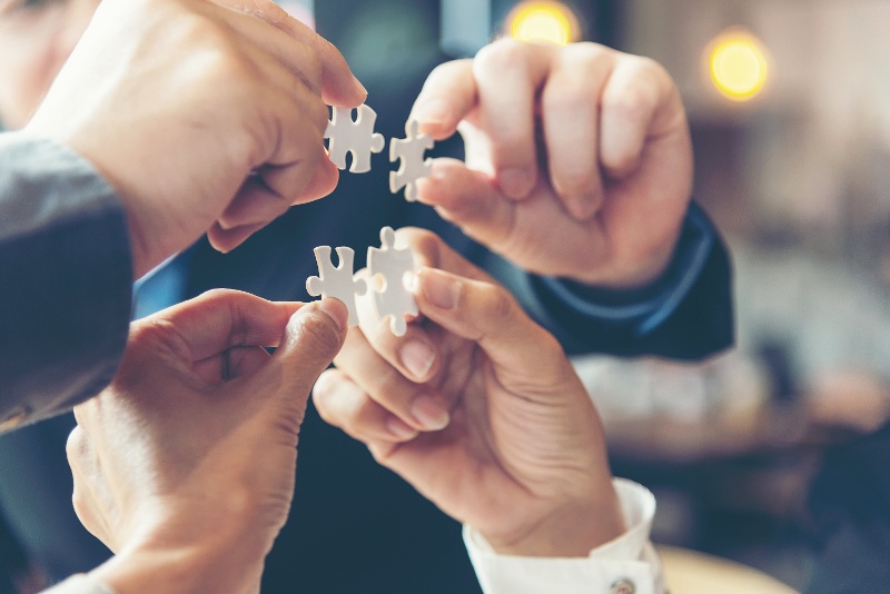 group of hands holding puzzle pieces together