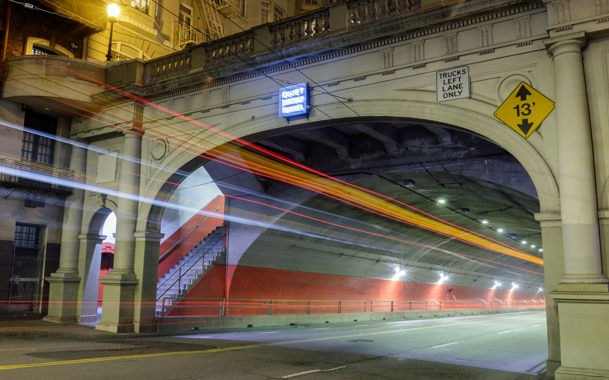 car lights trail through bridge